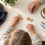 Child grouping five wooden counting tokens at home with adult support