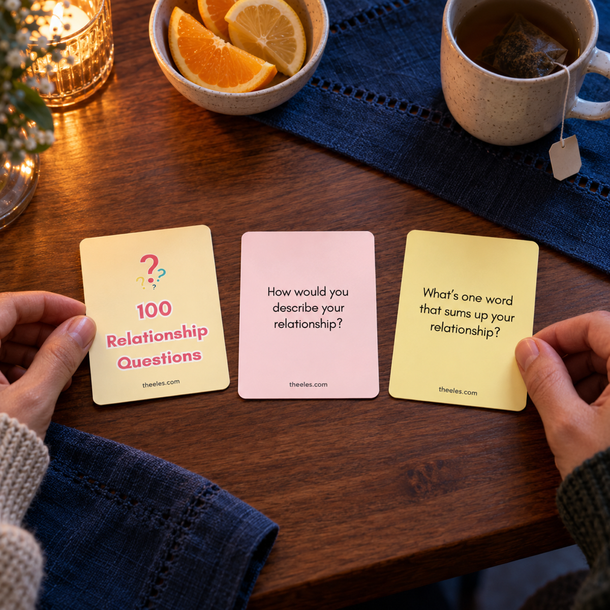 Three actual printable relationship question cards on a warm table, with two prompts readable